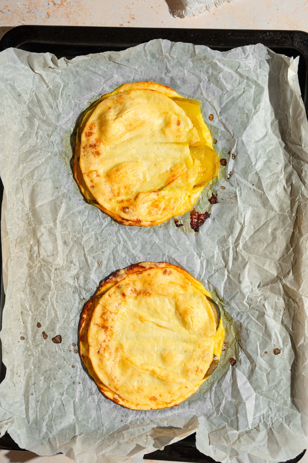 A baking sheet lined with parchment paper with two slices of baked pickle bread