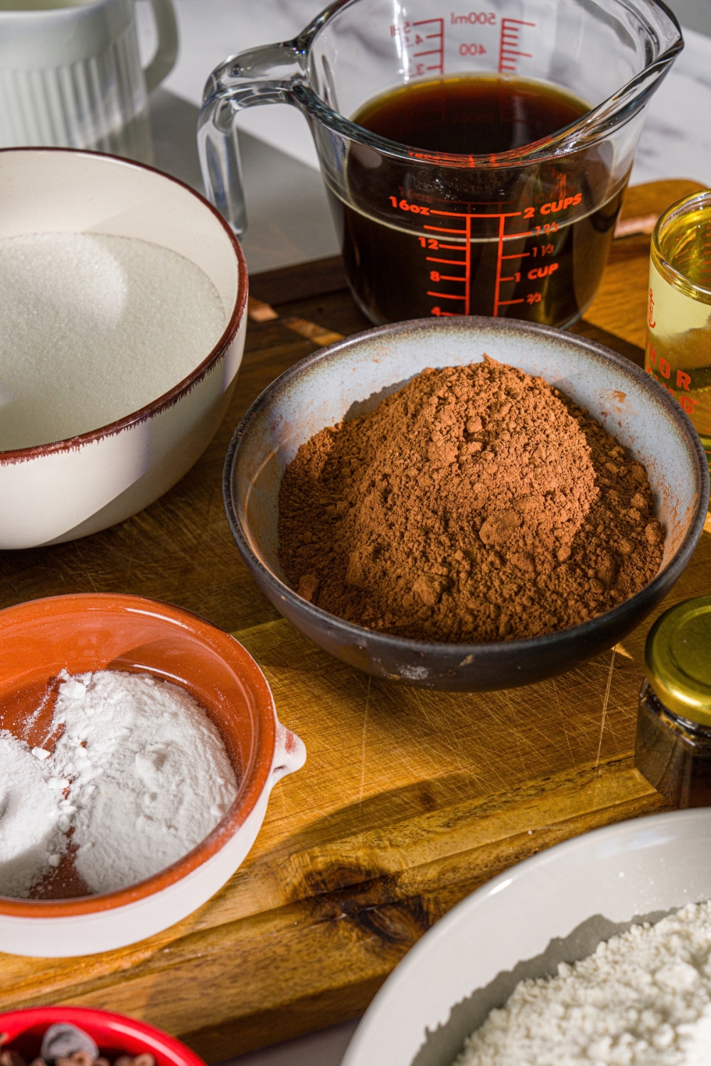 A wooden board with ingredients to make Matilda cake including cocoa powder, sugar, coffee, and more.