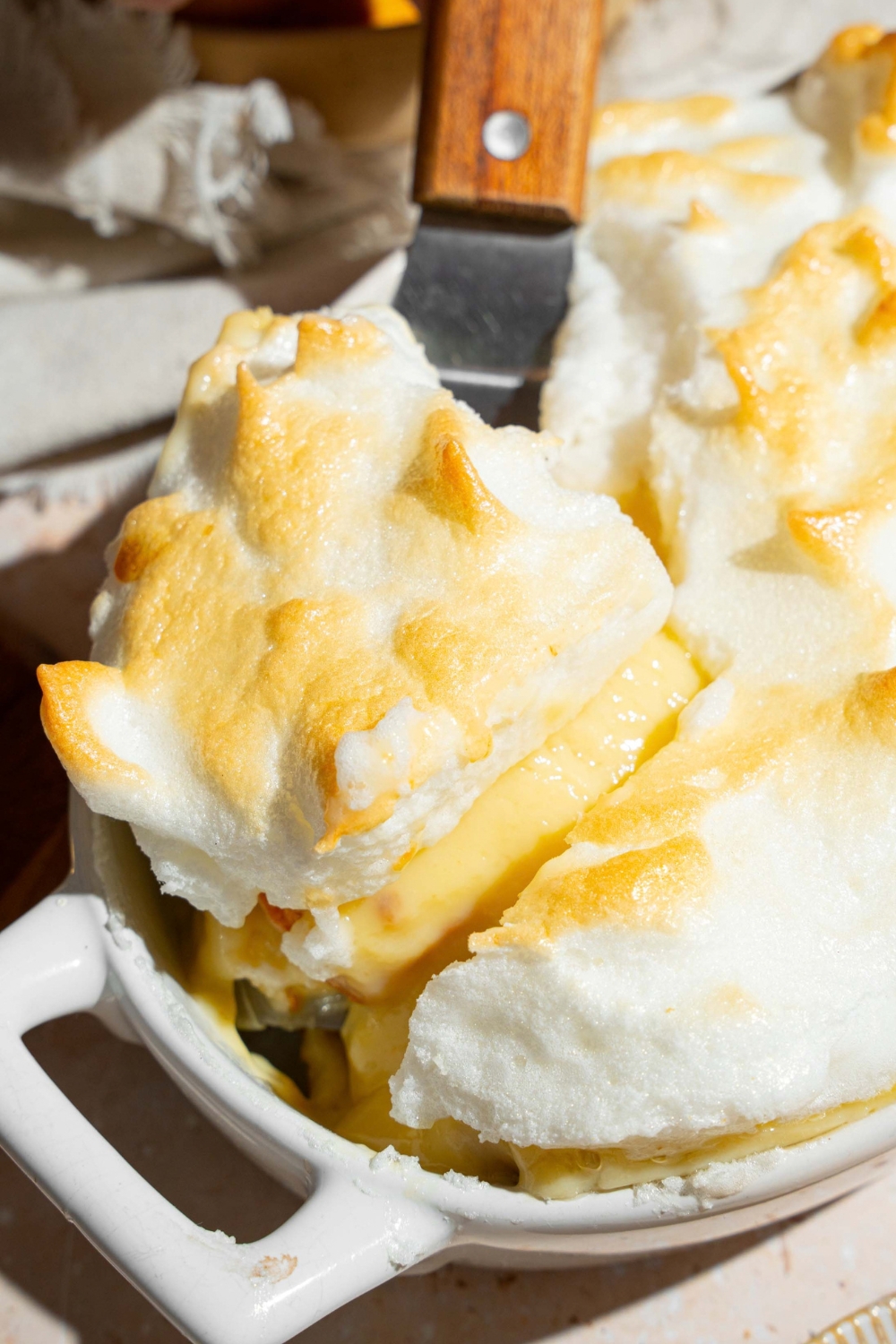A slice of Dolly Parton's banana pudding being pulled from a hole banana pudding that is into white casserole dish.