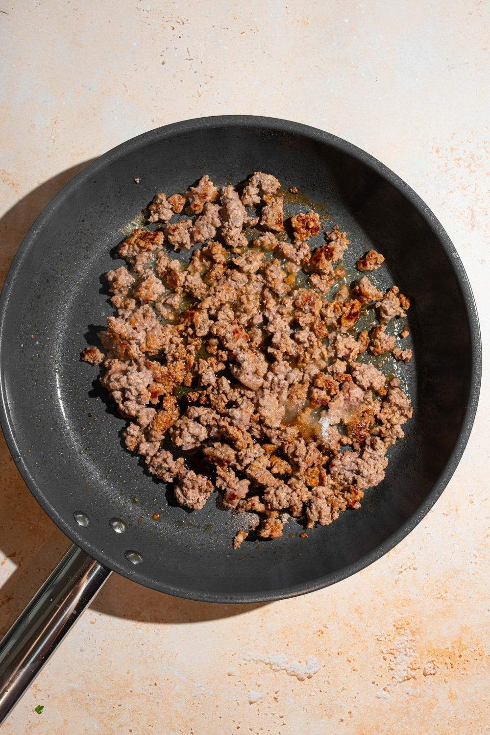 Ground beef cooking in a black skillet.