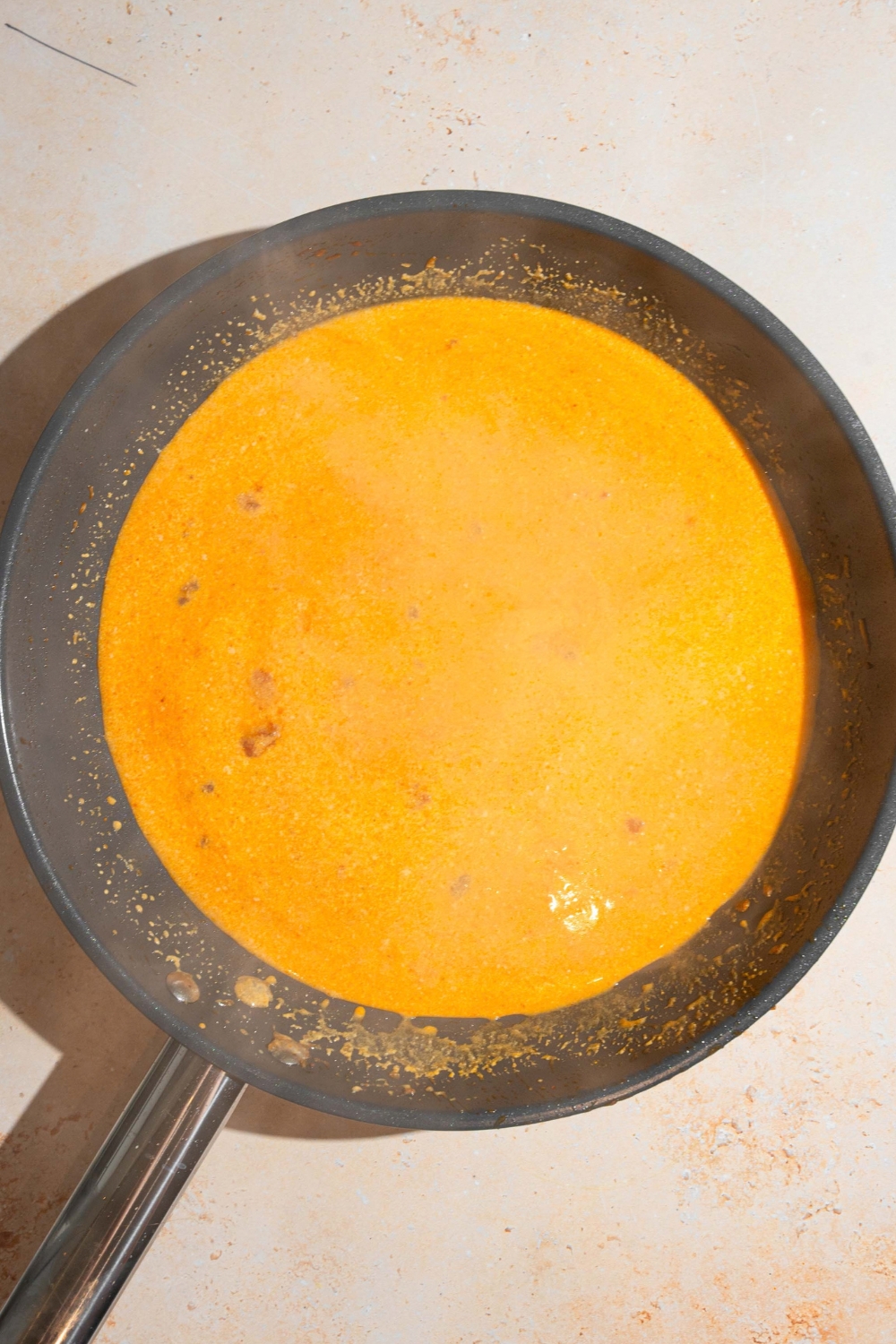 A coconut curry broth cooking in a black skillet.