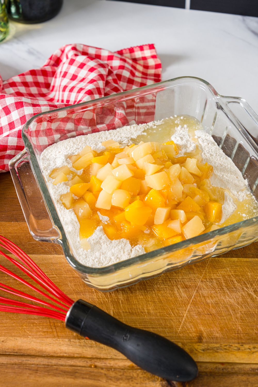 Fruit cocktail, sugar, and self rising flour in a glass ceramic dish.