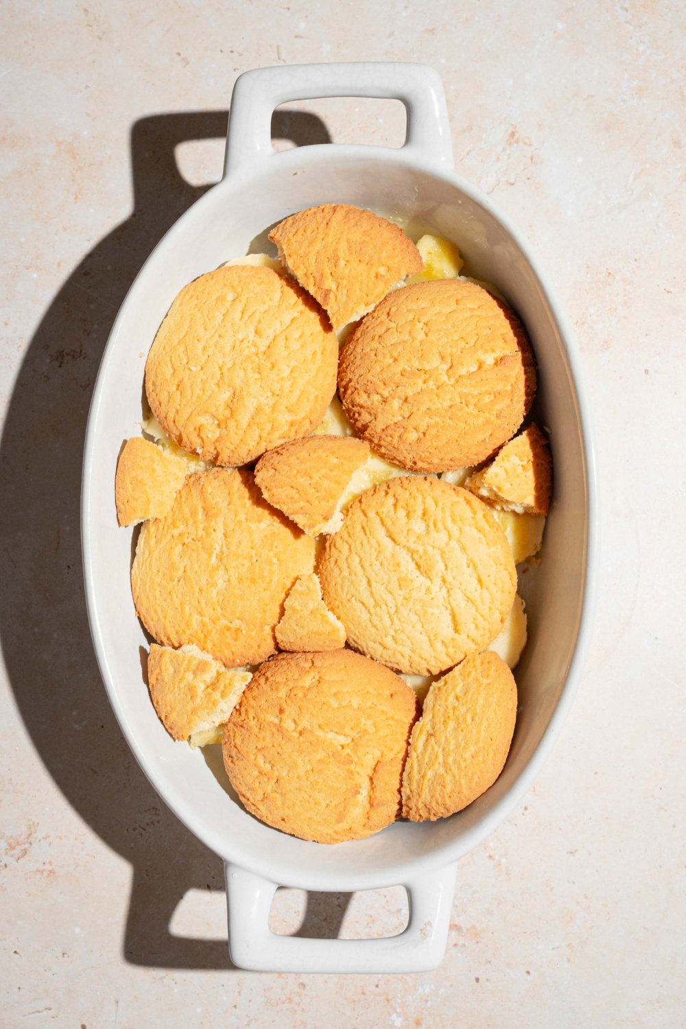 A bunch of vanilla wafer cookies on top of sliced banana bananas in a white casserole dish.