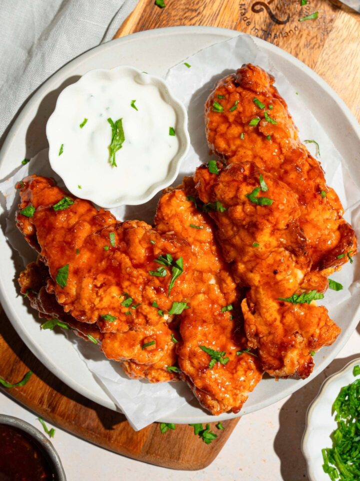 Sweet chili chicken tenders on a white plate with a side of ranch dressing.