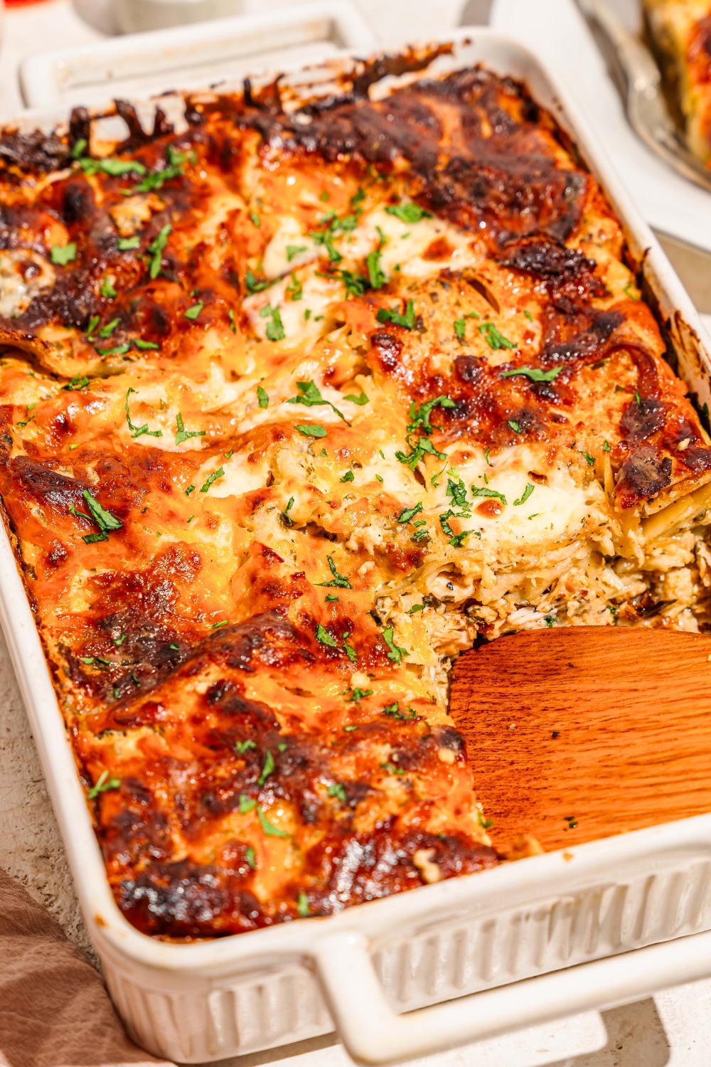 Chicken Alfredo lasagna bake in a white casserole dish.