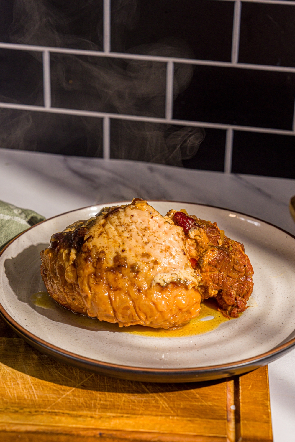A white platter with a whole slow cooked butterball turkey breast. The platter is on a wooden board.