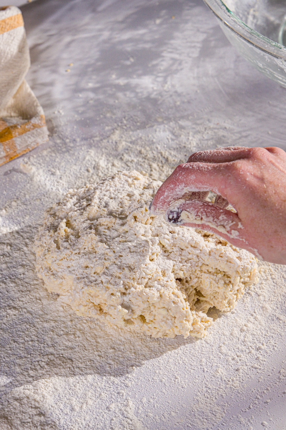A ball of Hardee's biscuit dough on a floured surface. Flour is being sprinkled on the dough.