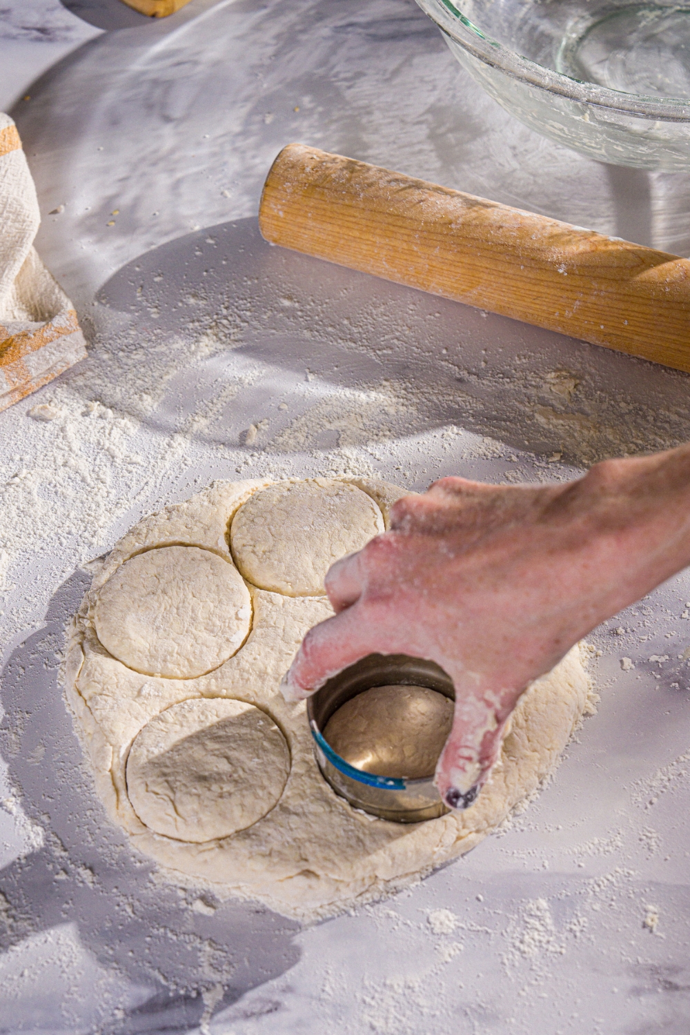 Hardee's biscuit dough rolled out on a floured surface with a biscuit cutter cutting into the dough.