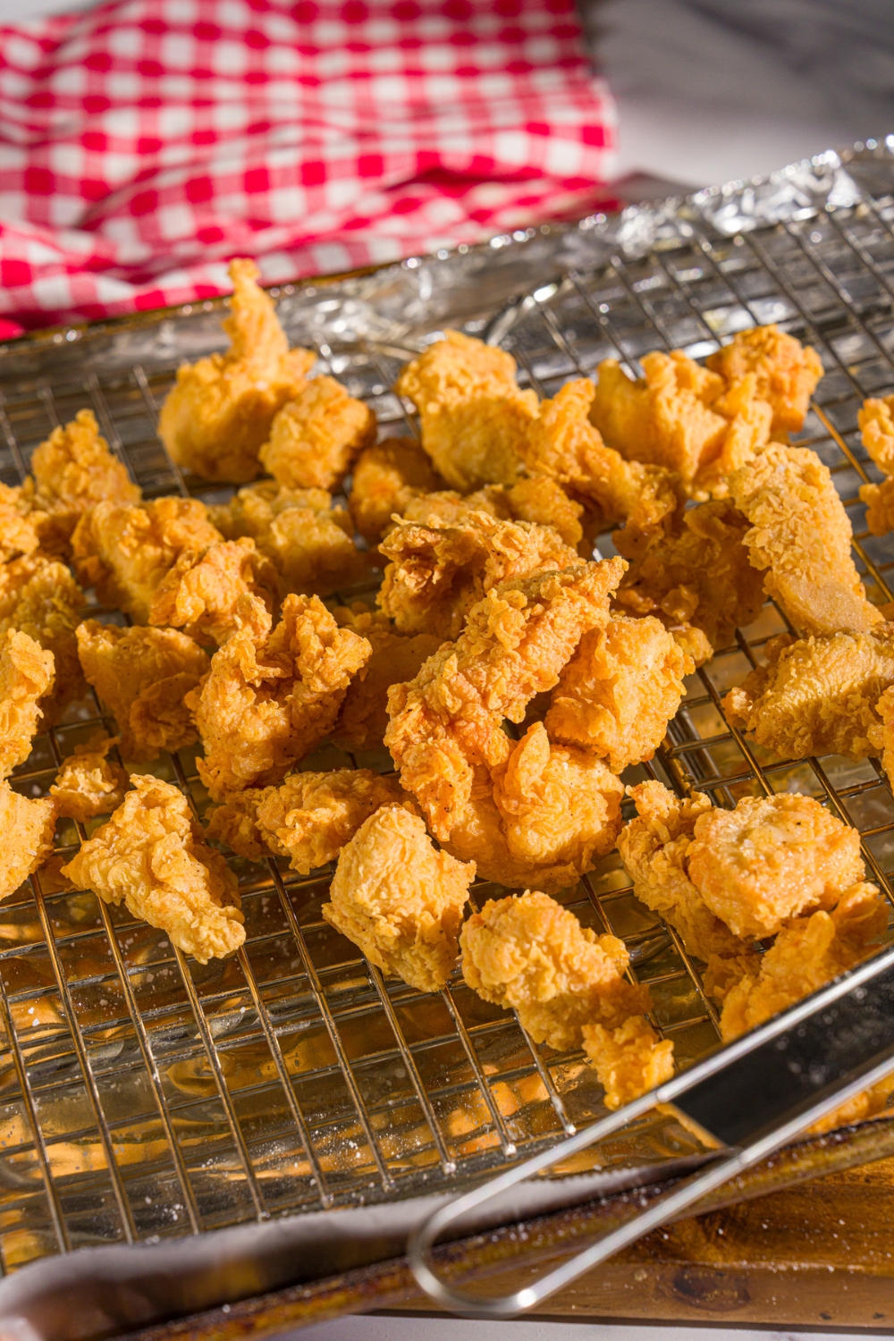 A baking sheet lined with foil and topped with a wire rack with fried popcorn chicken.
