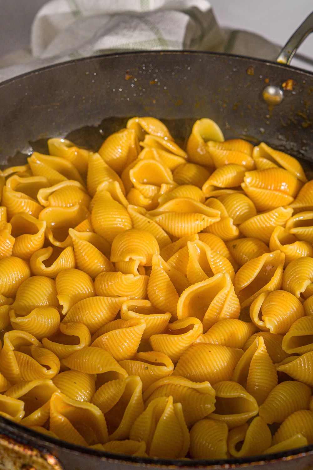 A skillet with pasta shells cooked in cajun cream sauce.