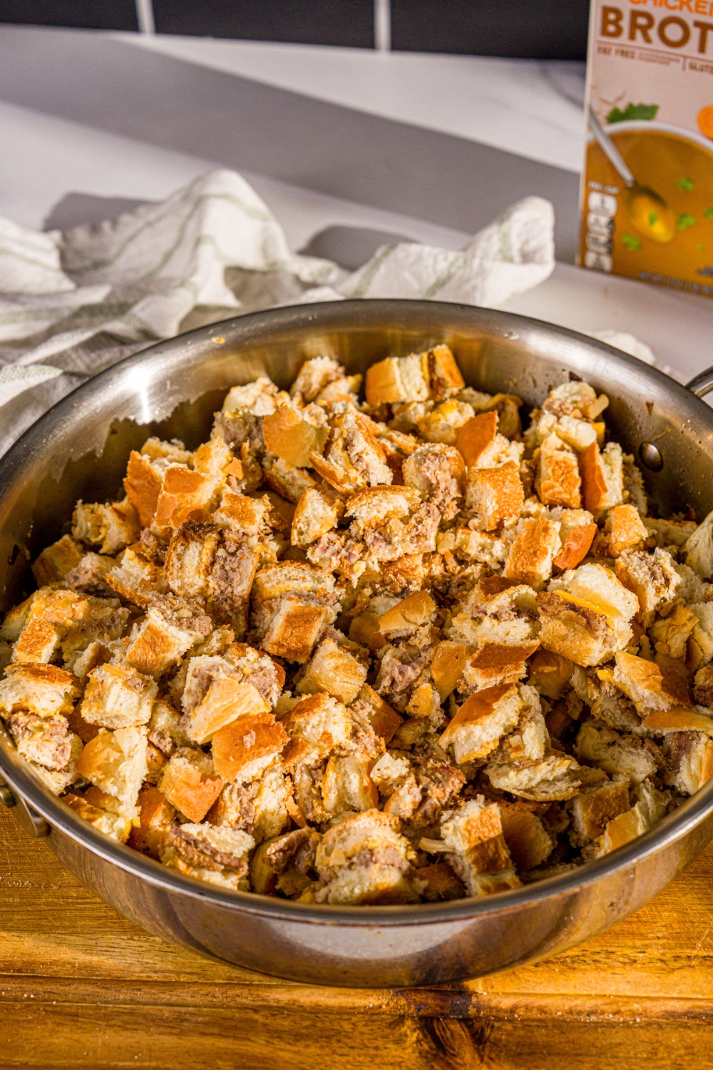A large skillet with sliced White Castle sliders with sautéd vegetables. The bowl is on a wooden board.