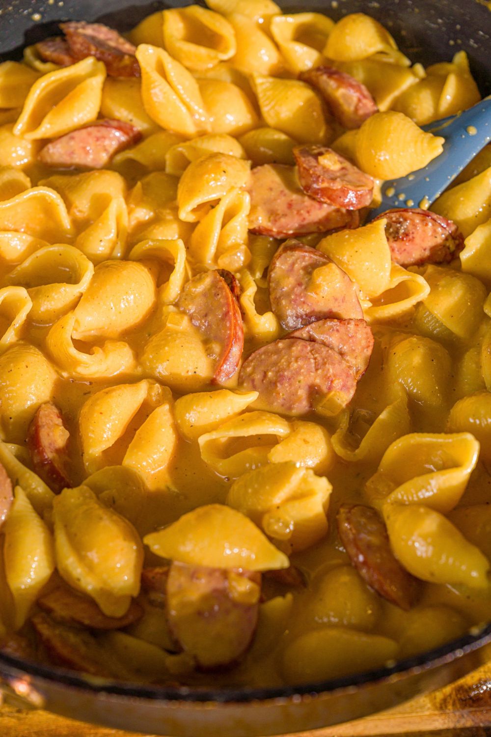 A skillet with cajun sausage pasta with shell pasta tossed in cajun cream sauce and sausage.