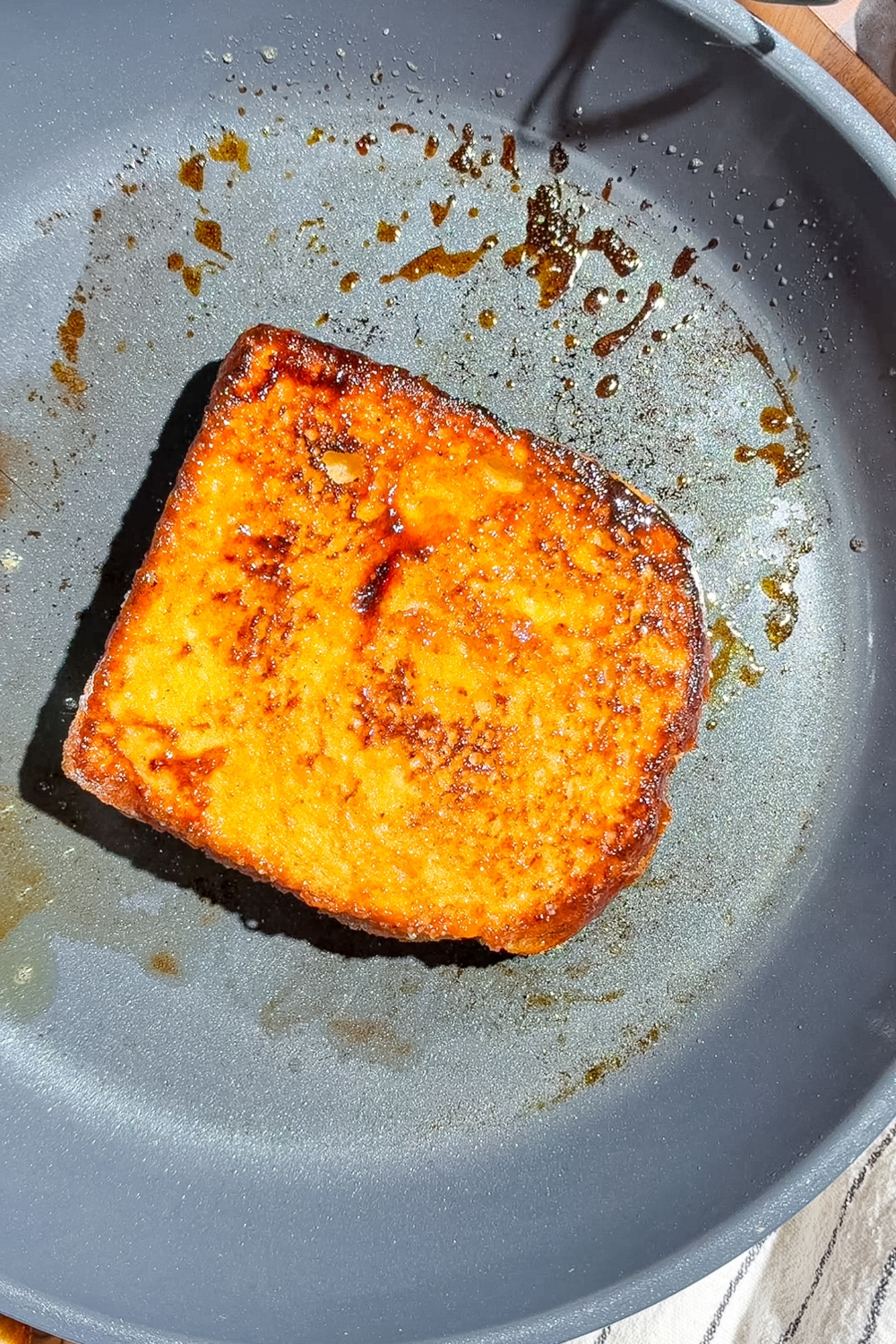 A skillet with a flipped slice of creme brulee french toast.