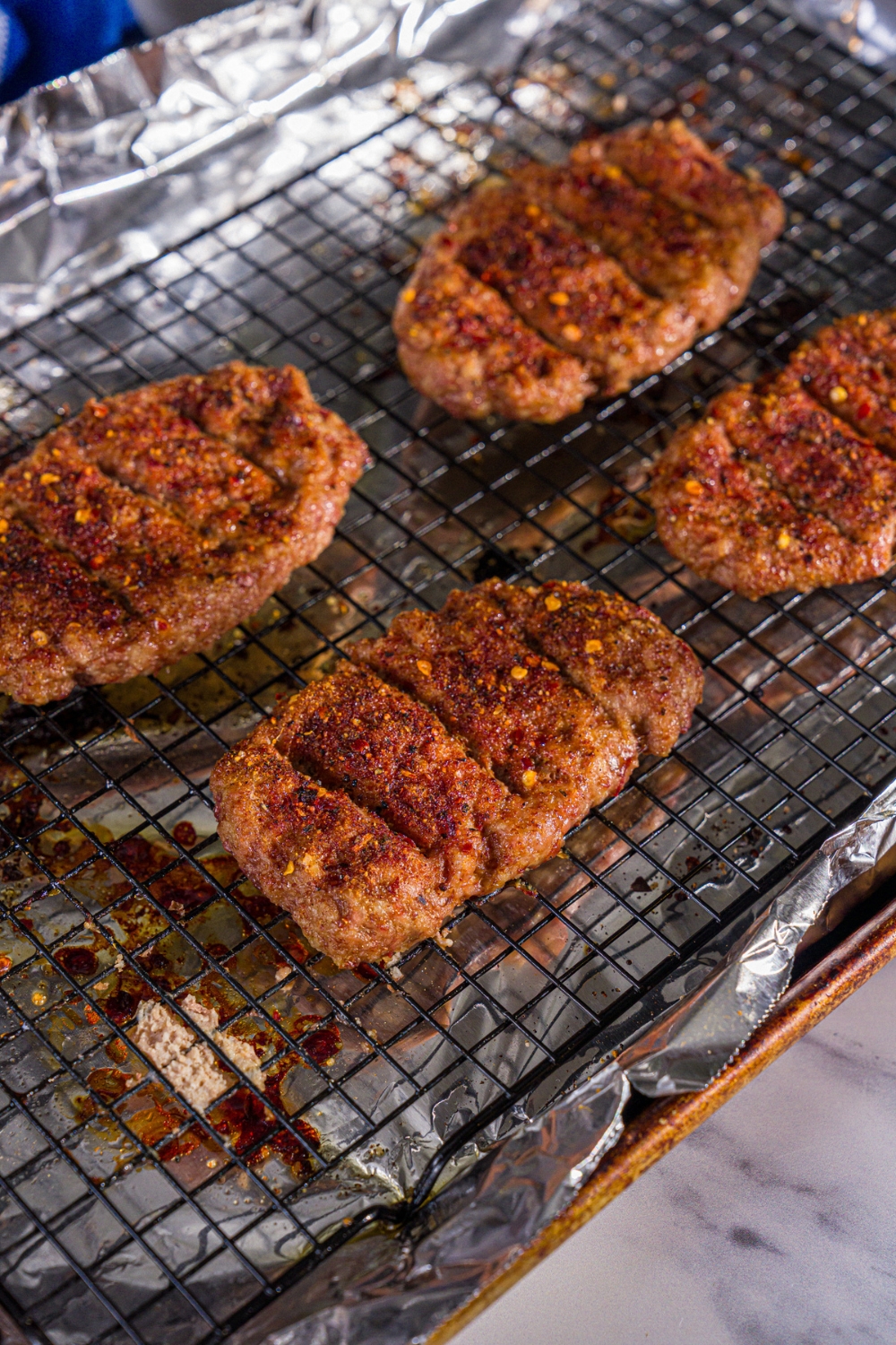 Baked seasoned McRib patties on a wire rack over a baking sheet lined with foil.