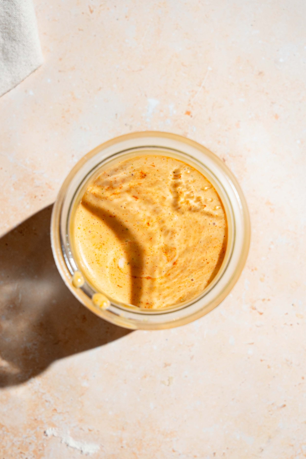 A blender jar with blended chipotle ranch dressing. The jar is on a tan counter.