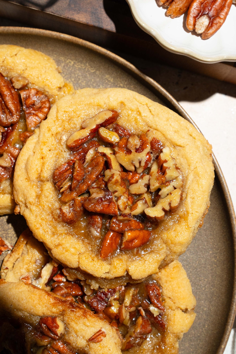 A plate with pecan pie cookies topped with pecan pie filling. The plate is on a tan counter.