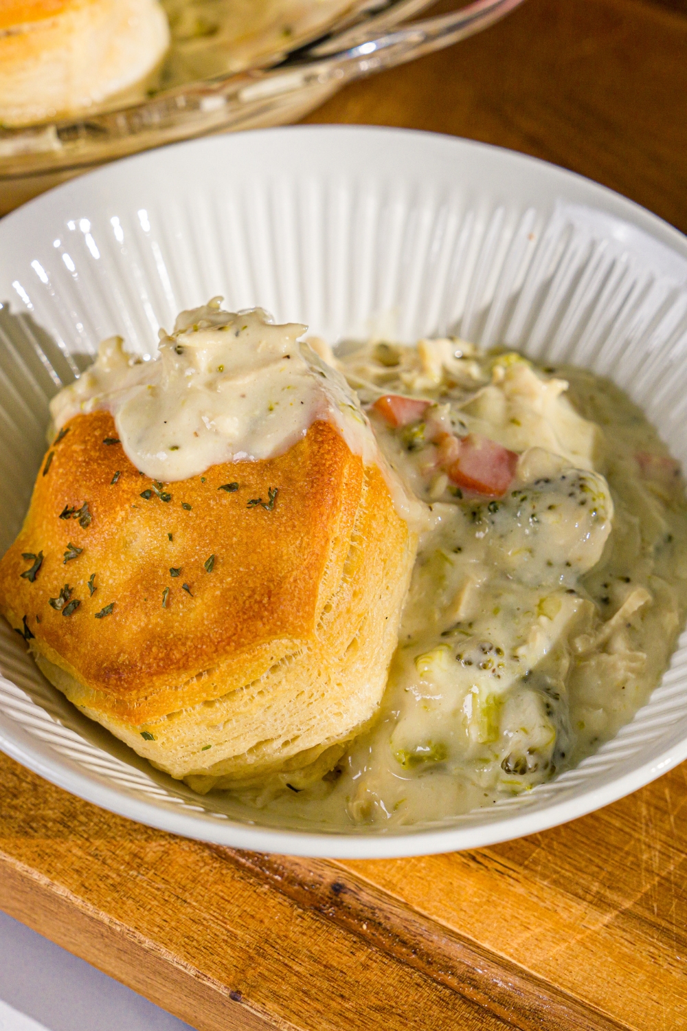 A bowl of Trader Joe's chicken pot pie with a biscuit topping. The bowl is on a wooden board.