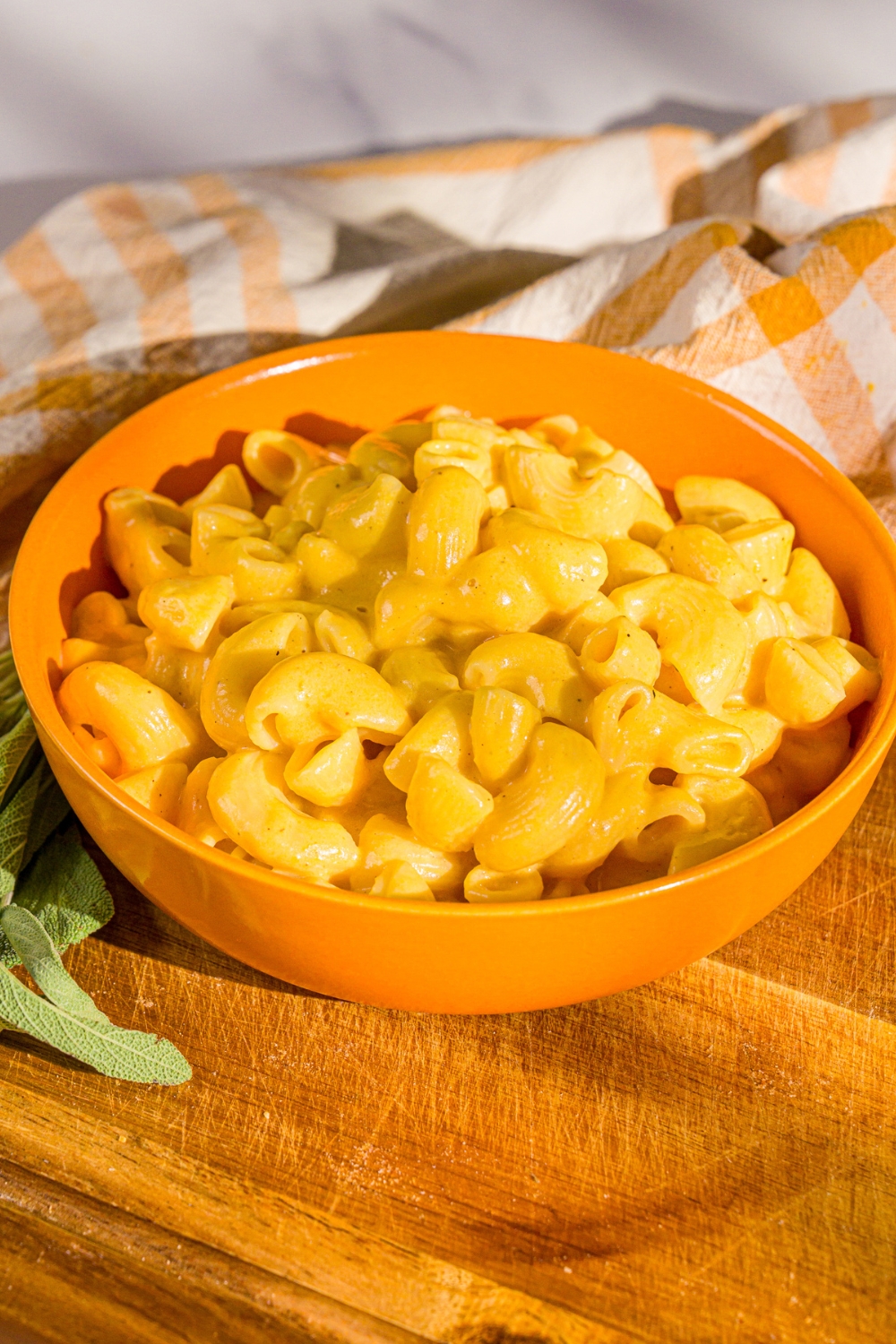 An orange bowl that is filled with butternut squash mac and cheese.