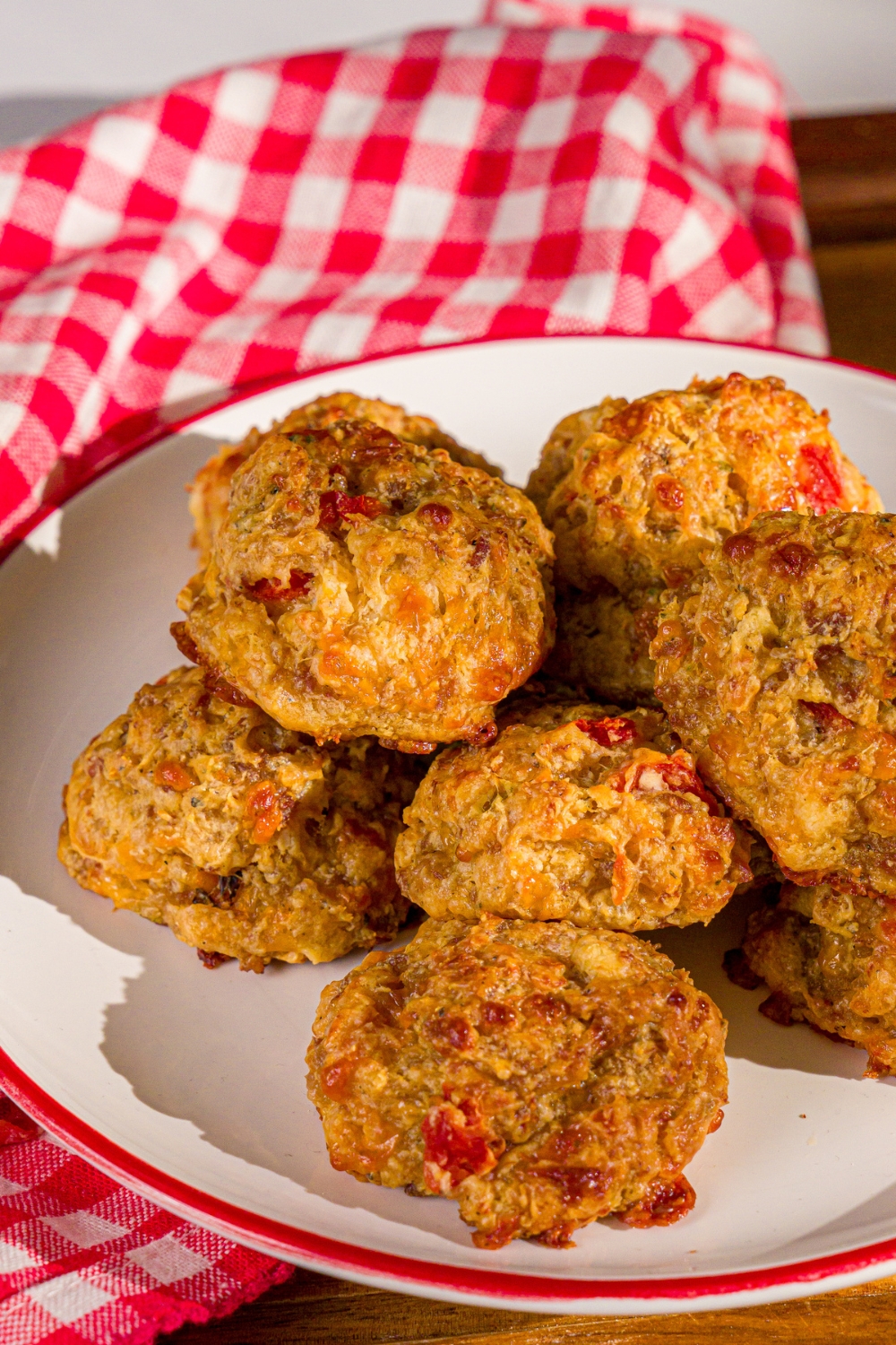 A plate of cheddar bay biscuit sausage balls. The plate is on a wooden board with a red checkered napkin.