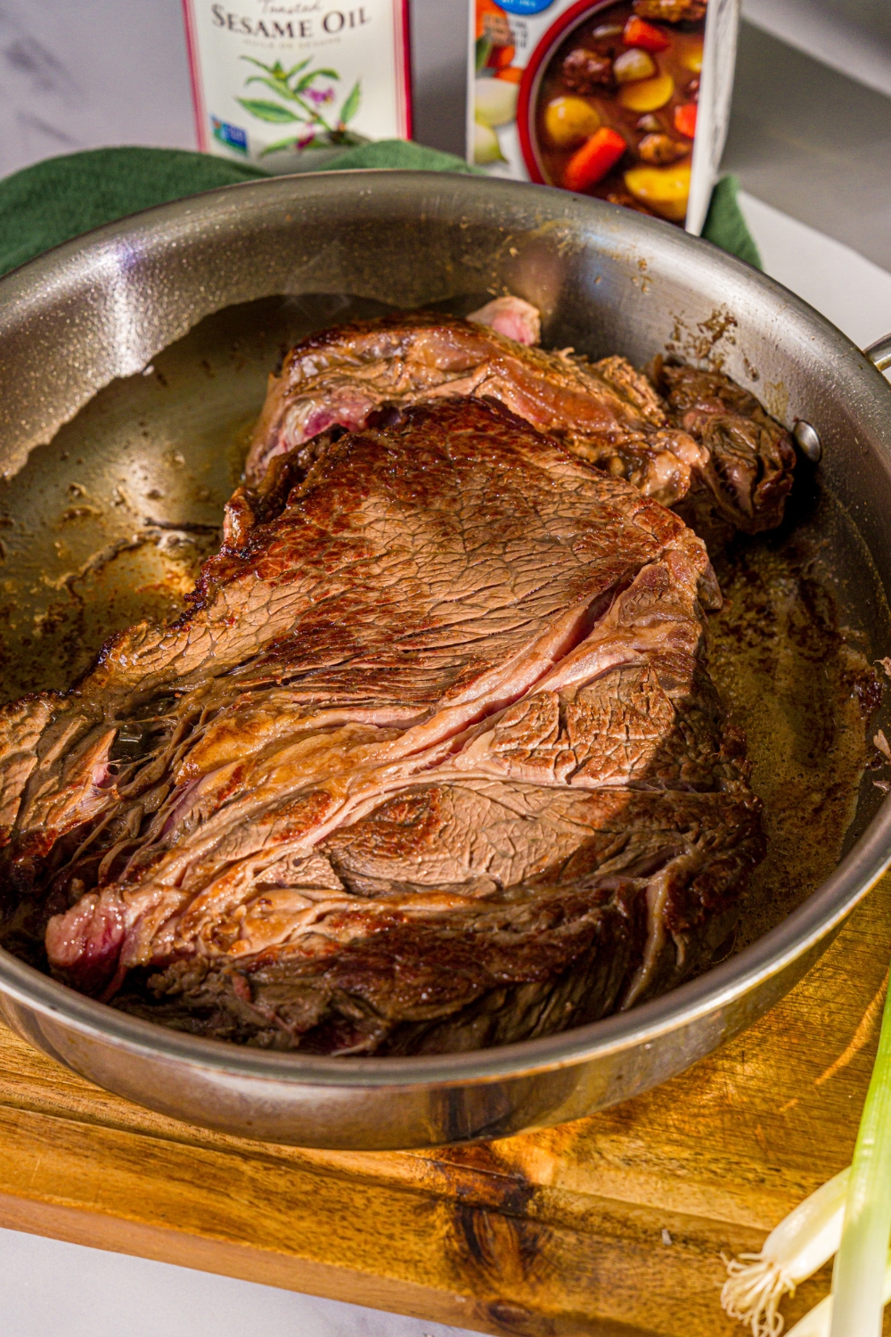 A large chuck roast searing in a pan for crock pot mongolian beef.