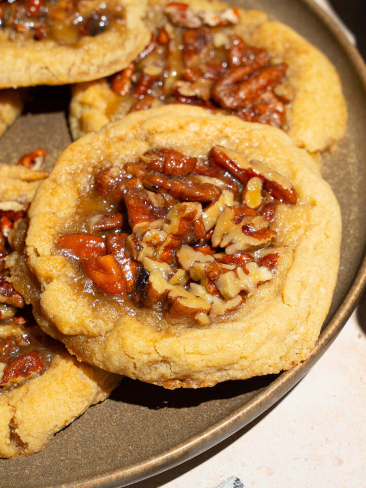 A pecan pie cookie on a grey plate with three other pecan pie cookies on the plate.