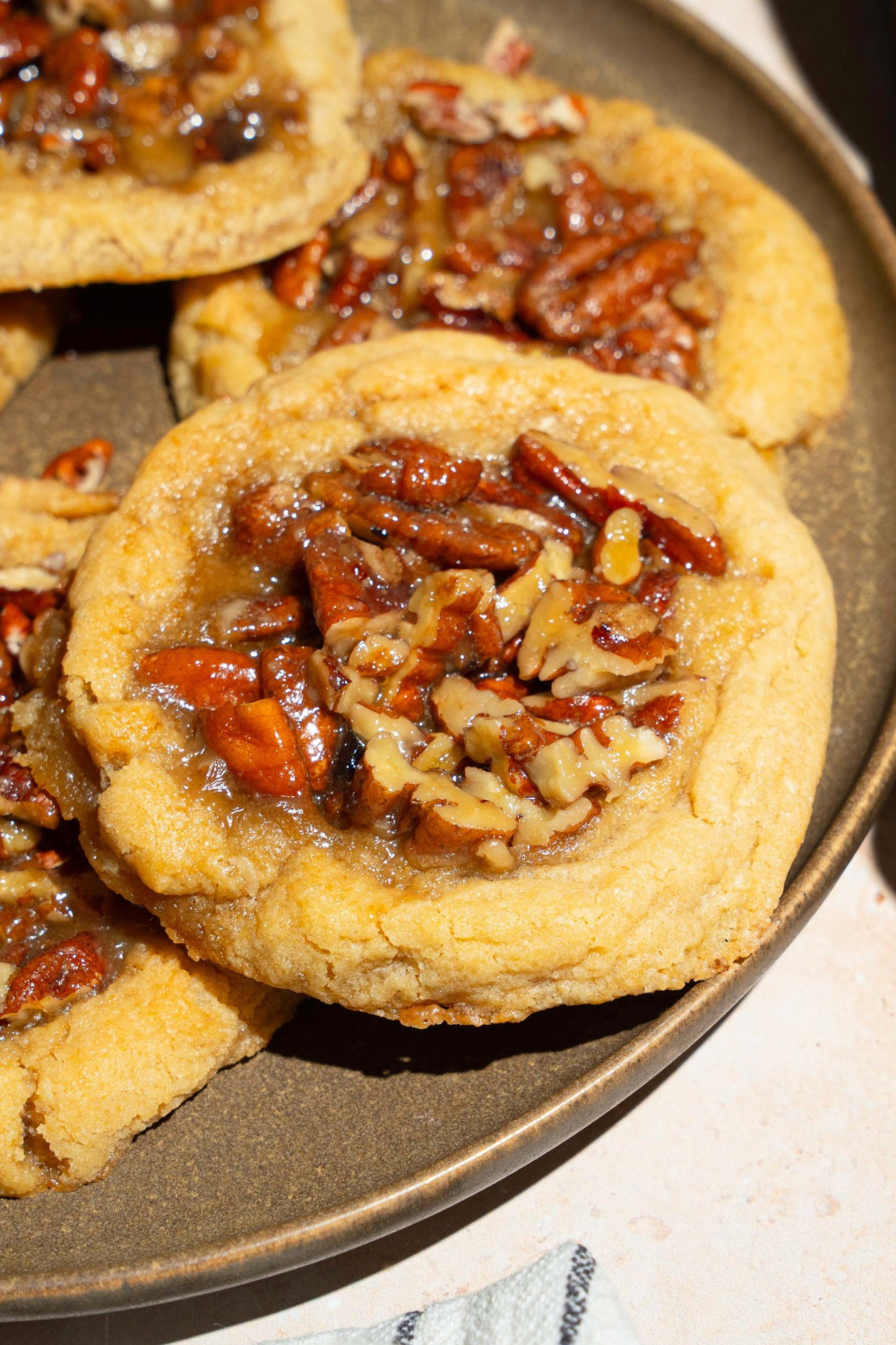 A pecan pie cookie on a grey plate with three other pecan pie cookies on the plate.