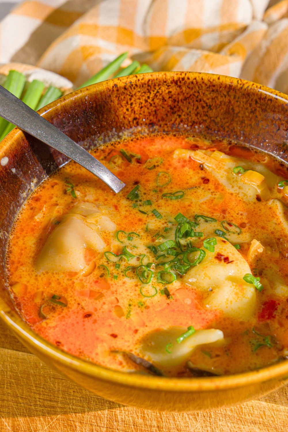 A brown bowl that is filled with potsticker soup.