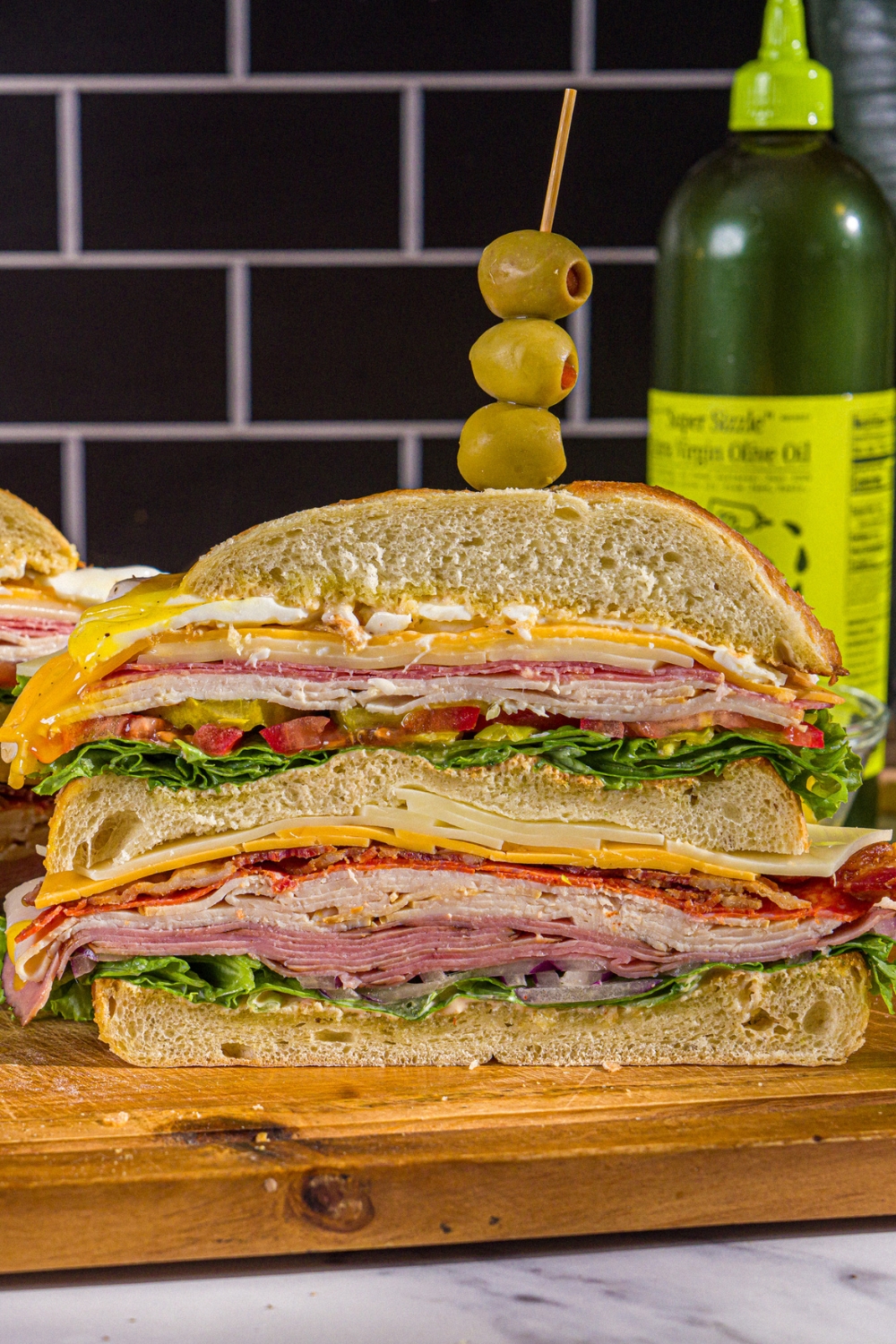 A half of a scooby doo sandwich with the inside of three layers of swiss and american cheese, lettuce, tomato, onion, and deli meats showing.