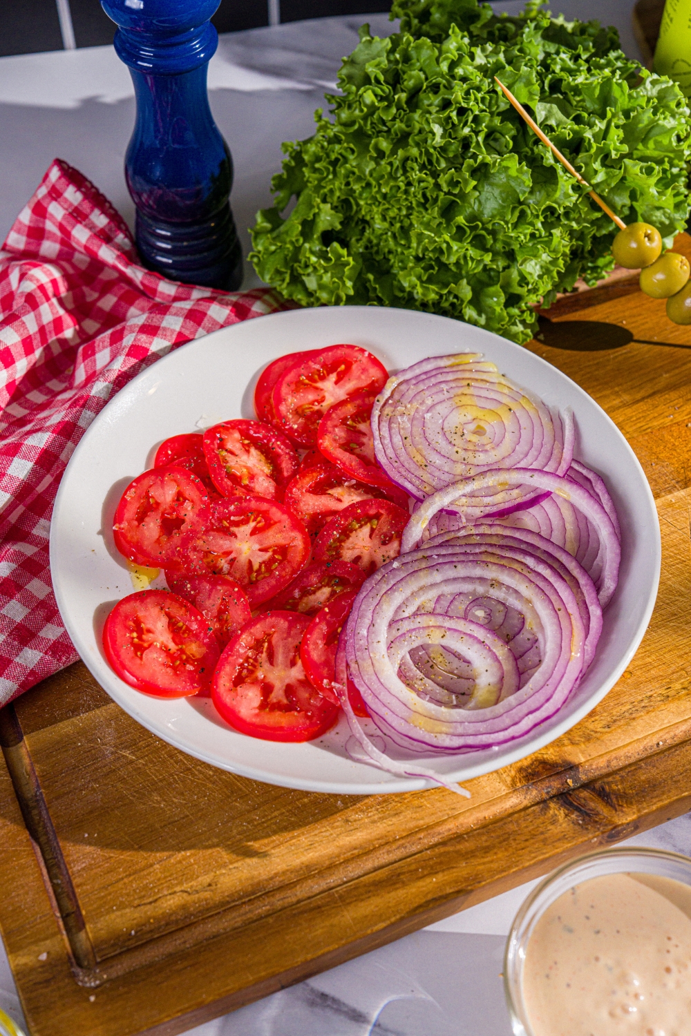 A white plate with sliced tomatoes and onions for a scooby doo sandwich.
