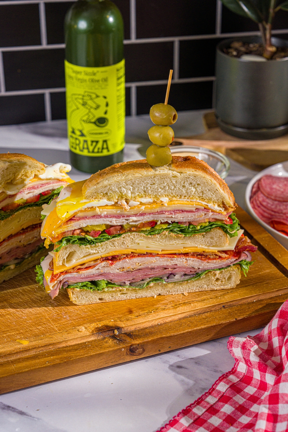 A scooby doo sandwich cut in half with the three layers of swiss and american cheese, lettuce, tomato, onion, and deli meats showing.