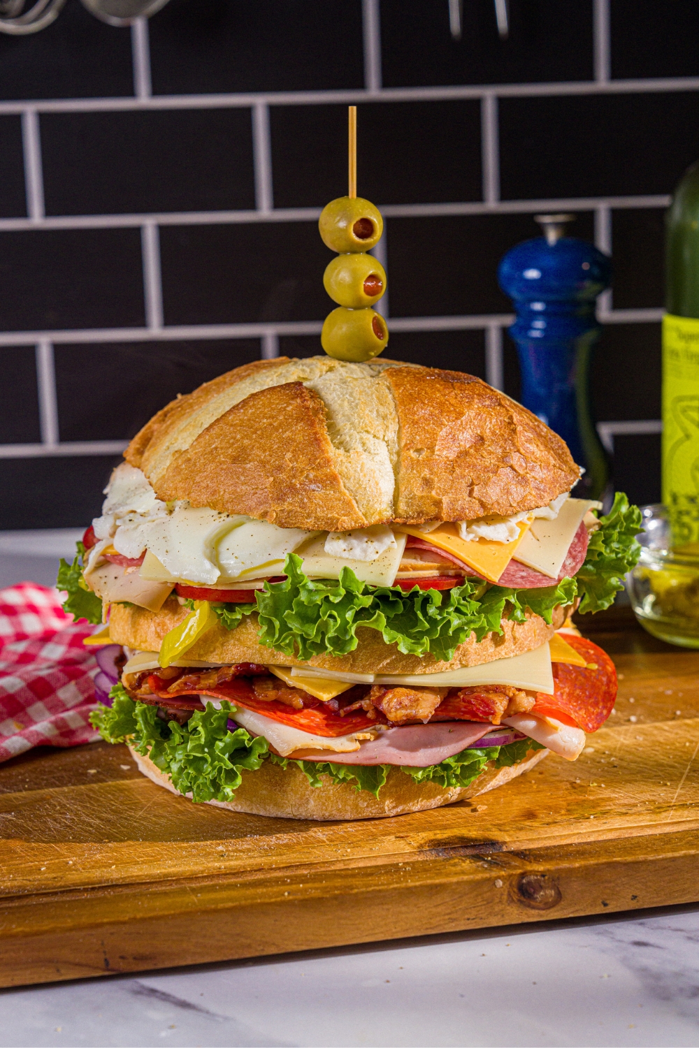 An assembled scooby doo sandwich consisting of three layers of swiss and american cheese, lettuce, tomato, onion, and deli meats.